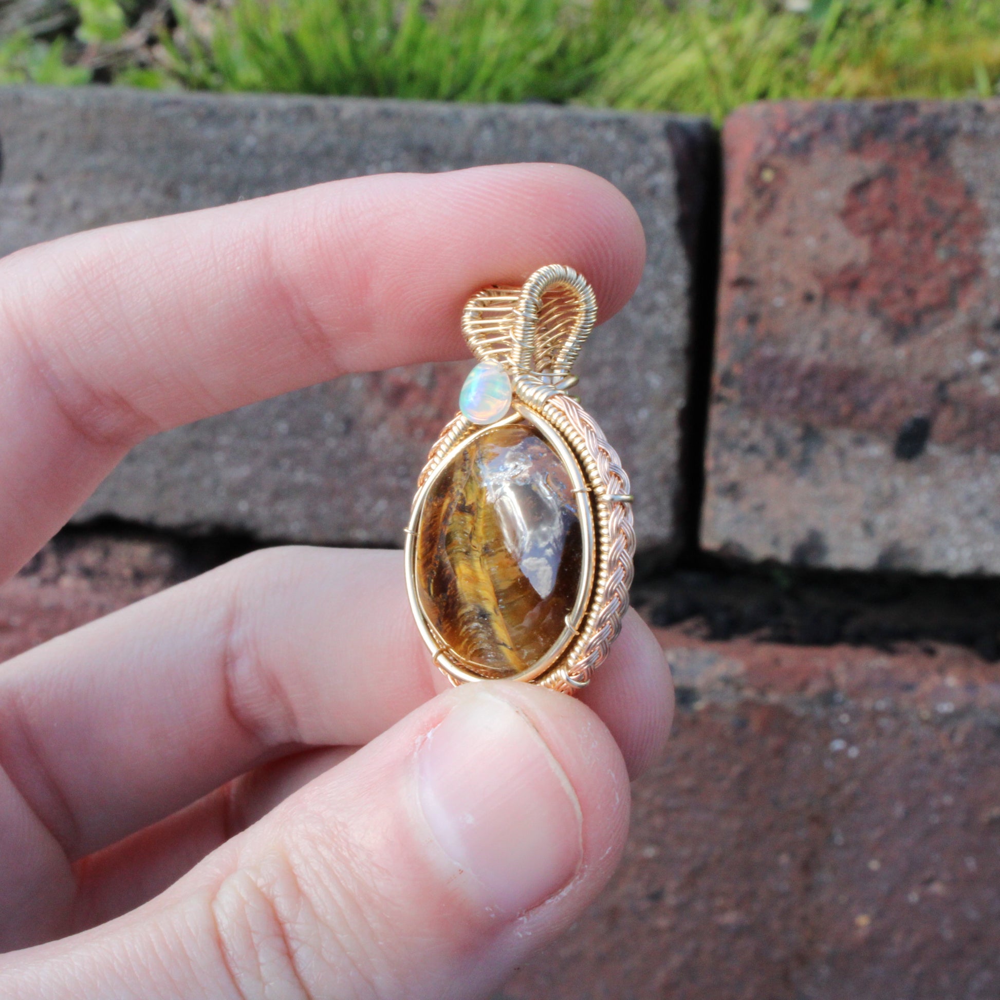 Tiger eye Ethiopian Opal 14k yellow and rose gold fill pendant held in hand with textured detailing