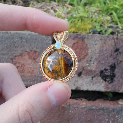 Tiger eye Ethiopian Opal 14k yellow and rose gold fill pendant held in hand with a natural background