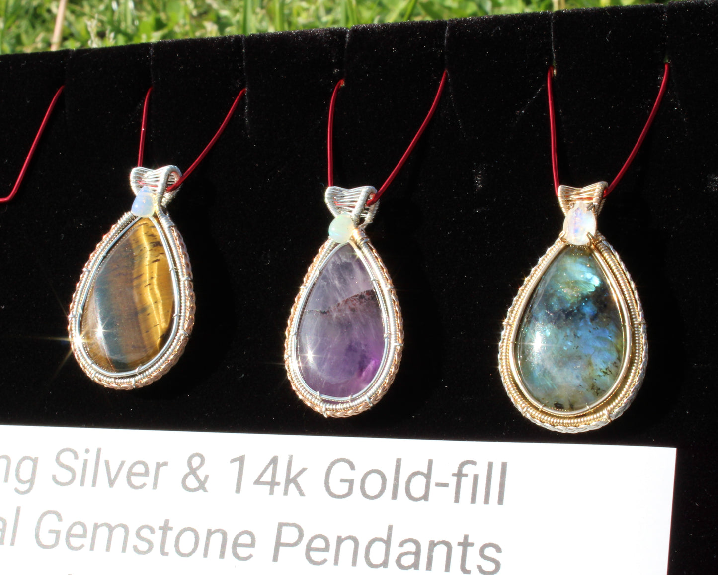 Tiger eye, Ethiopian opal sterling silver pendant surrounded by other gemstone pendants on display