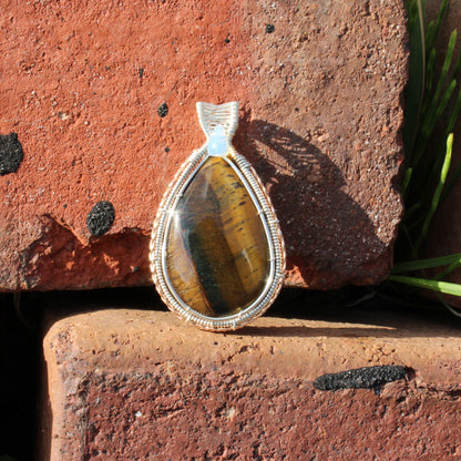 Tiger eye, Ethiopian opal sterling silver pendant displayed on a rustic brick background