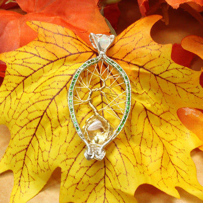 Silver Tsavorite tree of life pendant showcased on a colorful autumn leaf background