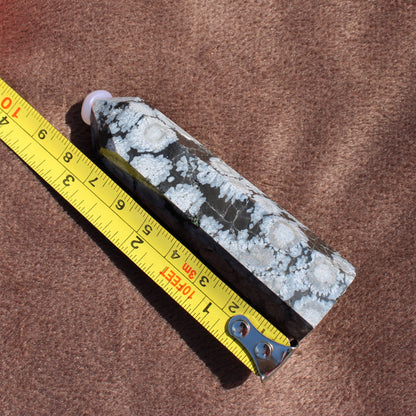 Snowflake Obsidian Tower crystal from Different Branches LLC next to a measuring tape showing size