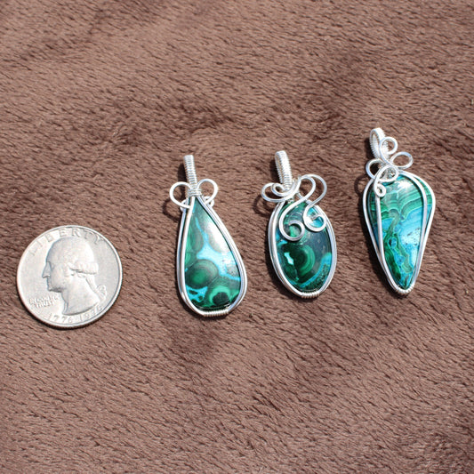 Sterling Silver Chrysocolla Malachite pendants with intricate wire wrapping displayed next to a quarter for size