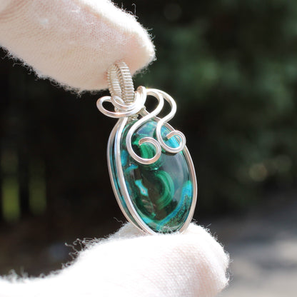 Sterling Silver Chrysocolla Malachite pendant with intricate wire wrapping held by gloved 