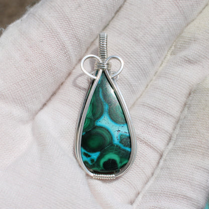 Sterling silver chrysocolla malachite teardrop pendant held in a white-gloved hand