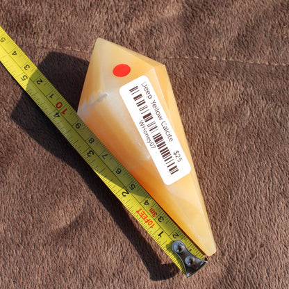 Yellow Calcite Wand crystal with measuring tape on brown fabric by Different Branches LLC